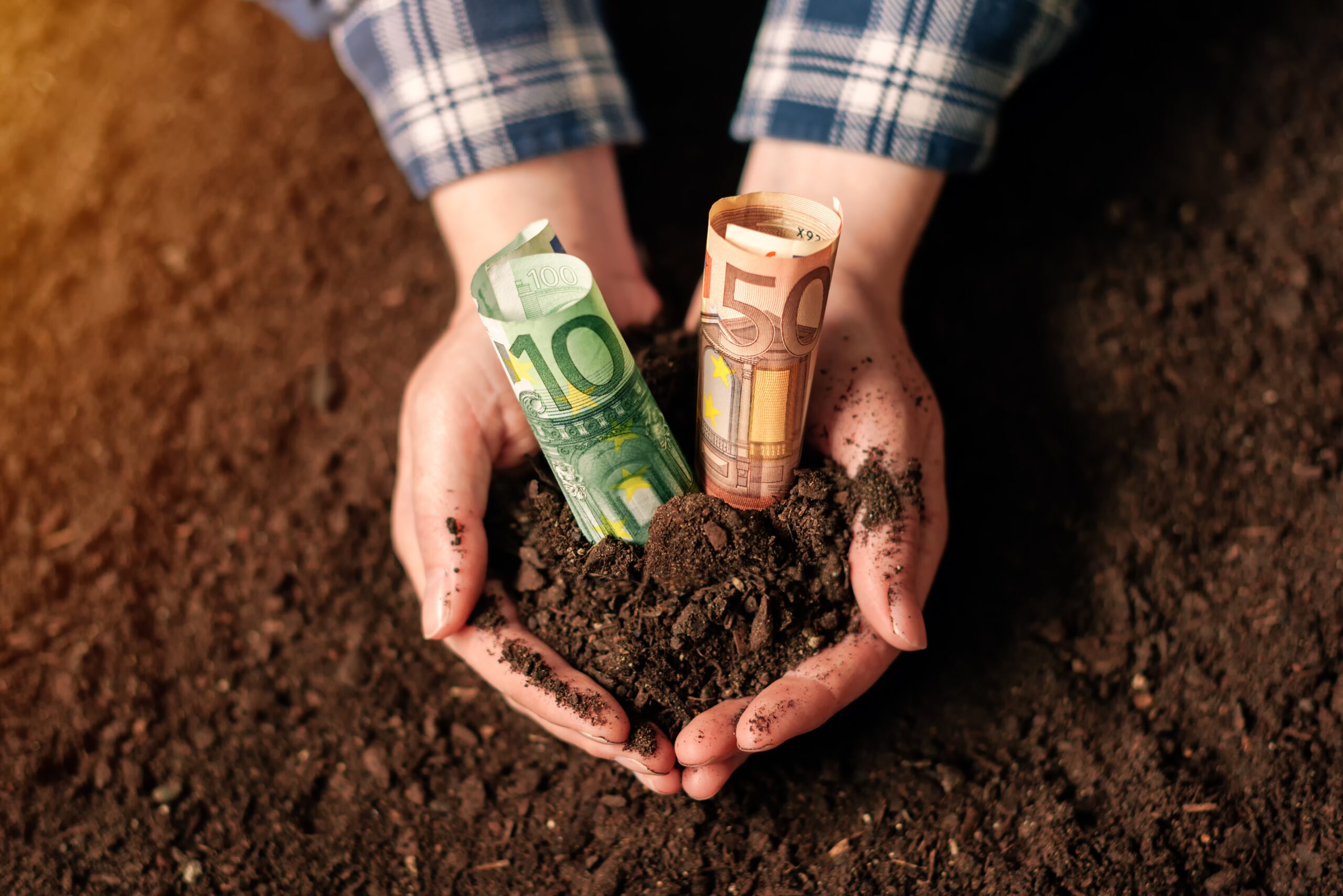 Hands with fertile soil and euro money banknotes Hands with fertile soil and euro money banknotes, female farmer handful of cultivated land that makes profit and steady income from sustainable agricultural activity like organic growth of crops