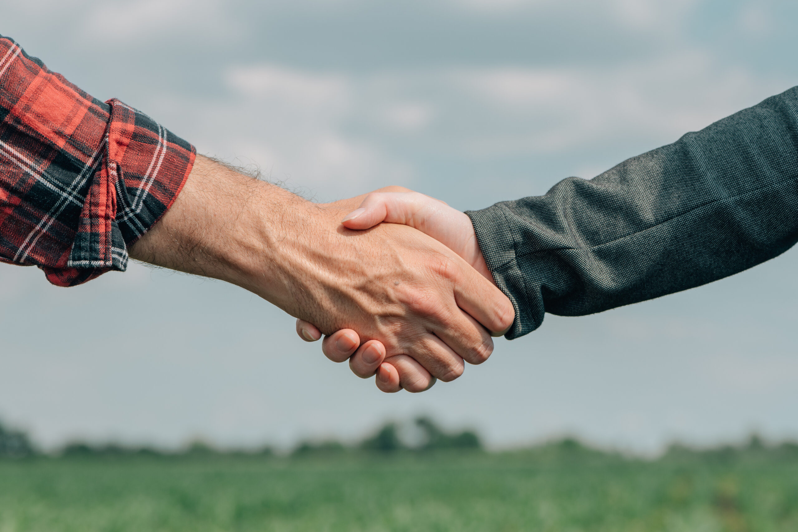 Mortgage loan officer and farmer shaking hands upon reaching an agreement Mortgage loan officer and farmer shaking hands upon reaching an agreement for financial allowance application, banker and farm worker in corn maize crop field.